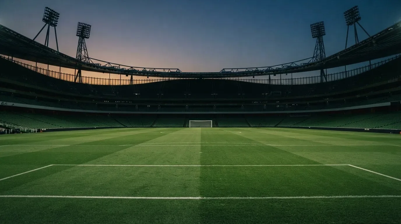 An empty football stadium with floodlight masts at dusk