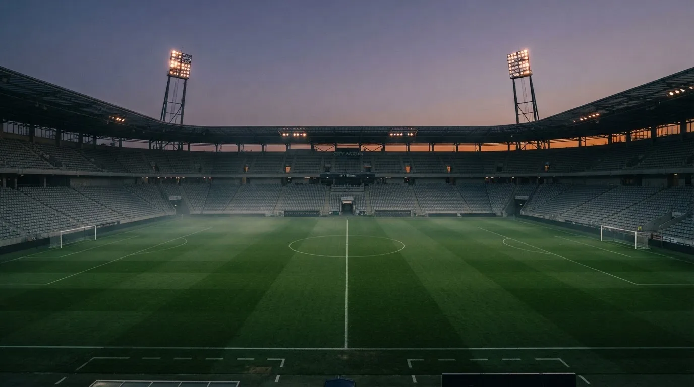 An empty football stadium with floodlight masts at dusk