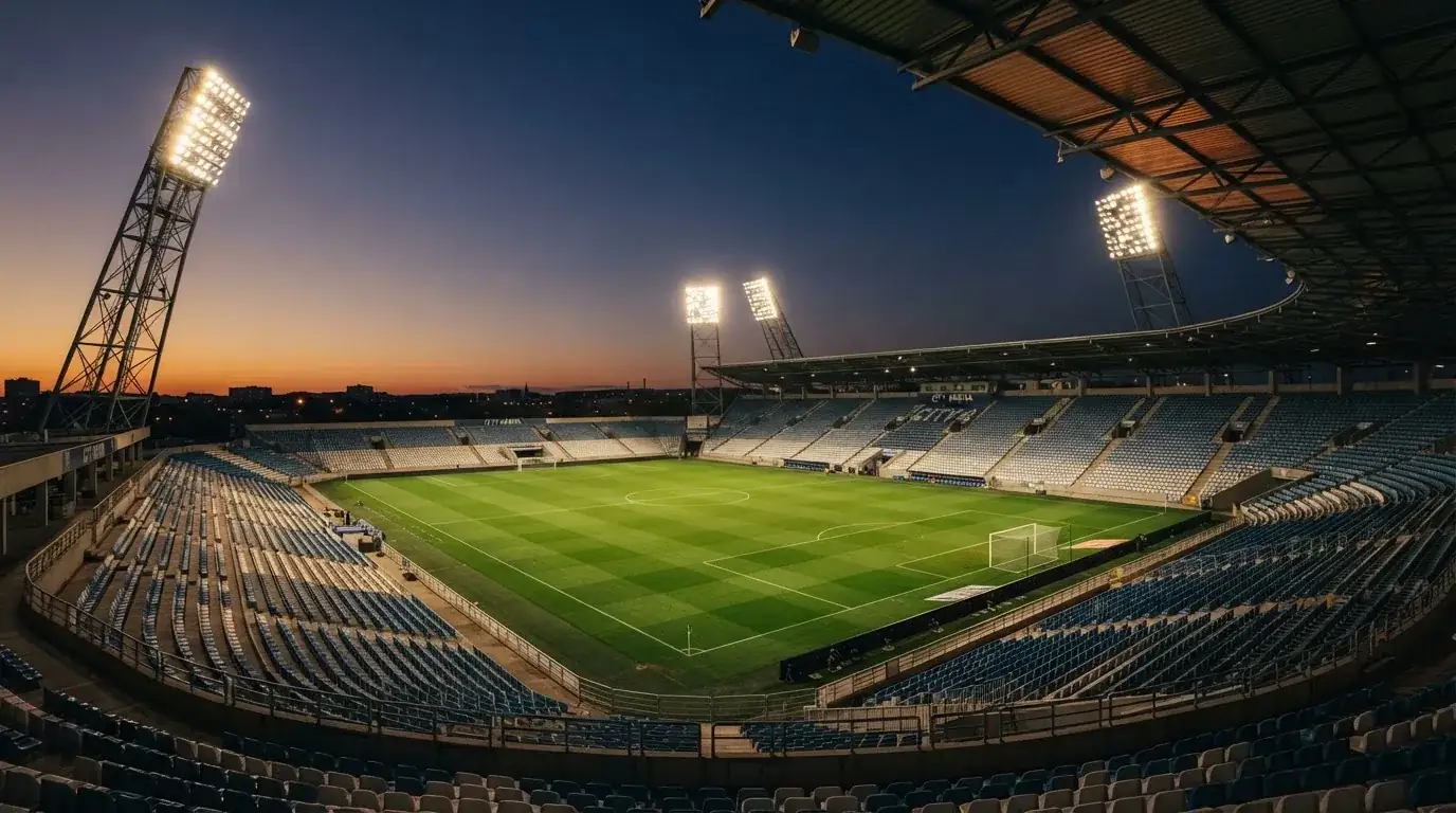 An empty football stadium with floodlight masts at dusk