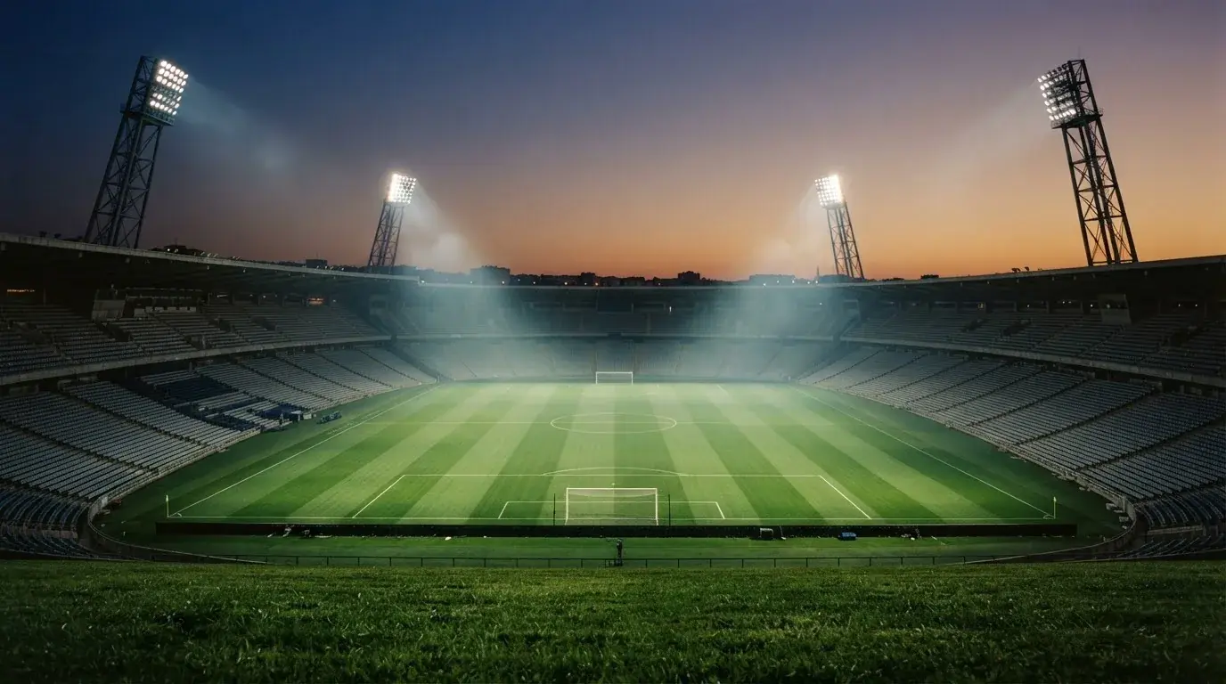 An empty football stadium with floodlight masts at dusk