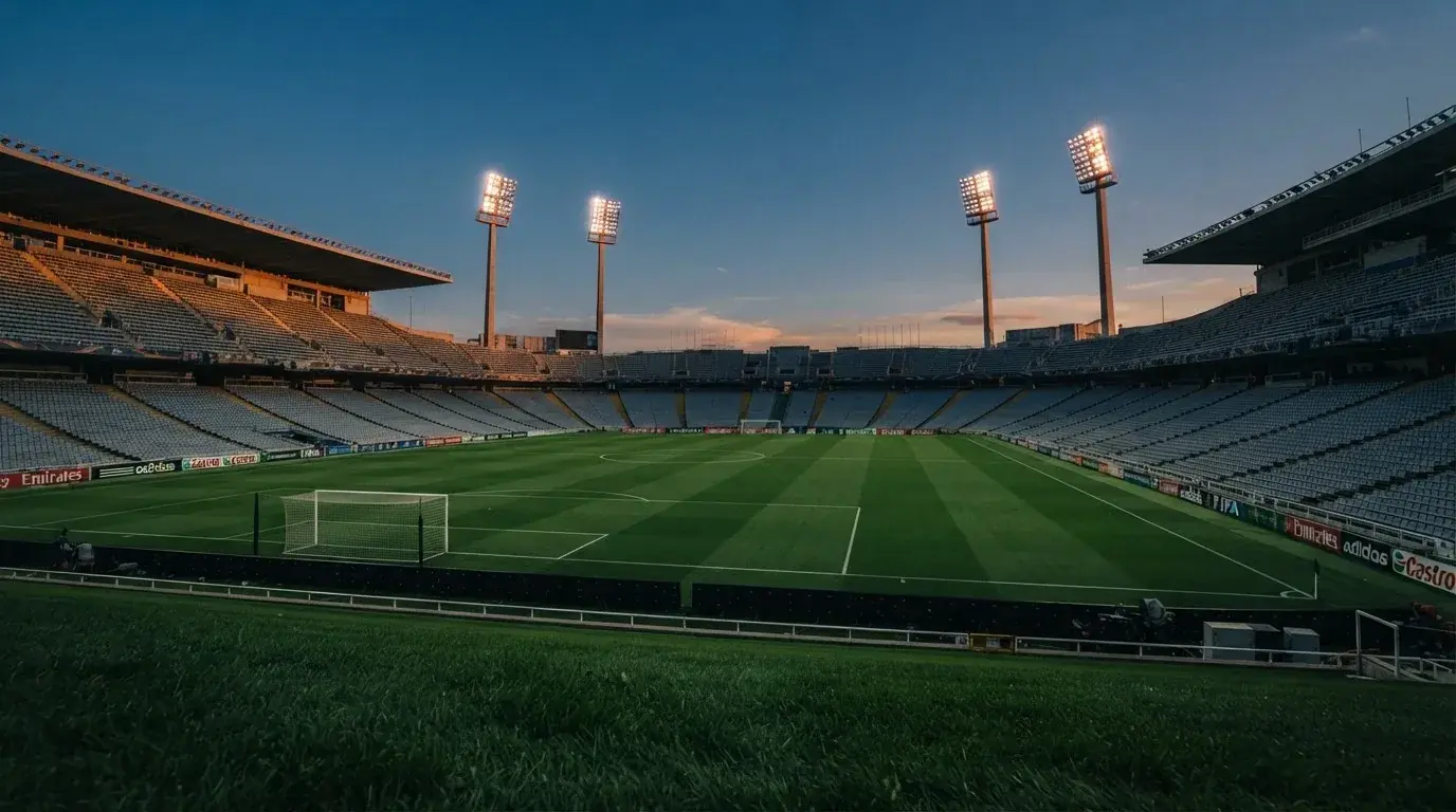 An empty football stadium with floodlight masts at dusk