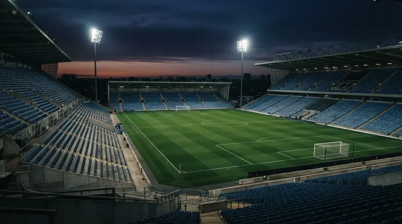 An empty football stadium with floodlight masts at dusk