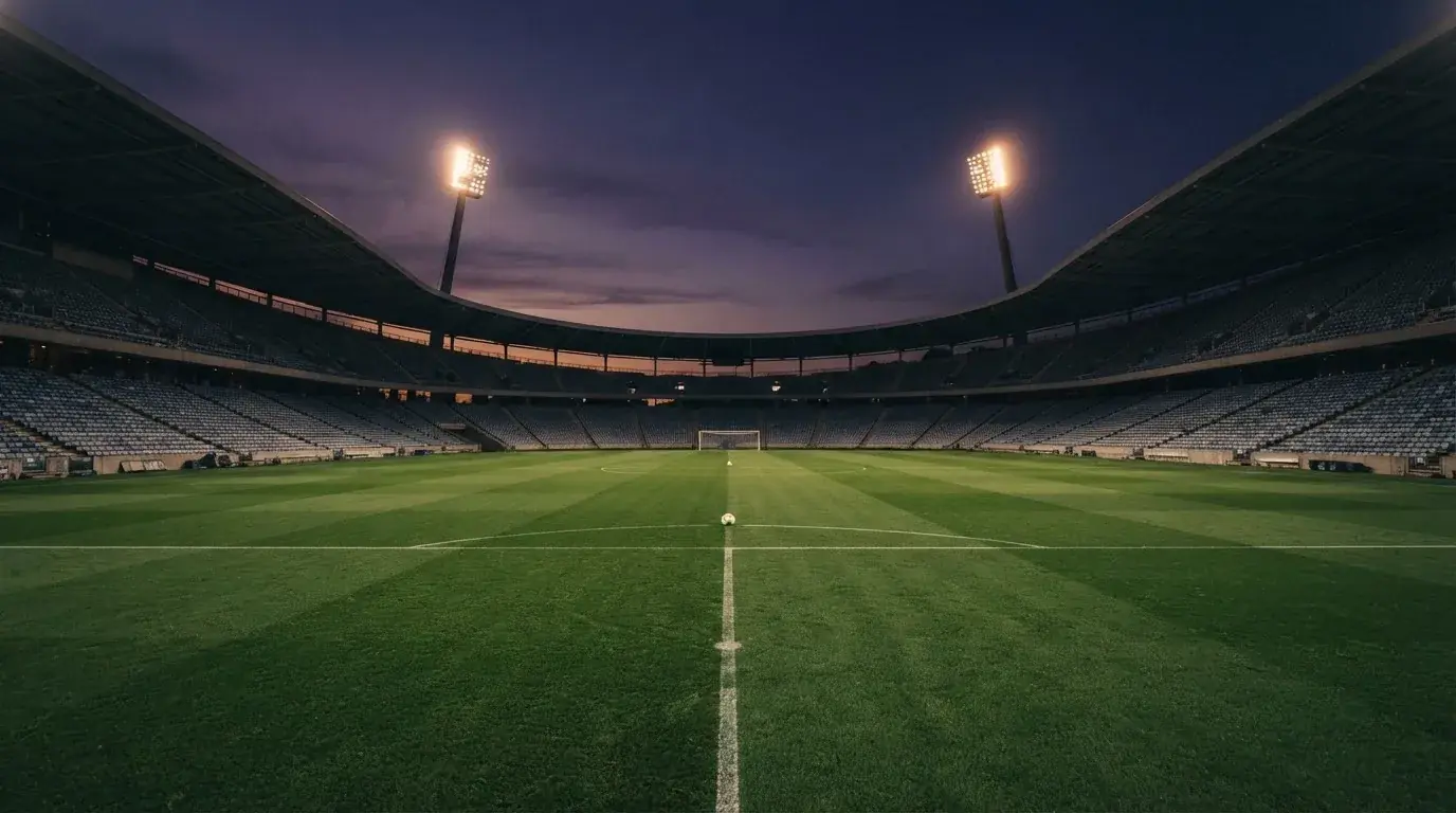 An empty football stadium with floodlight masts at dusk