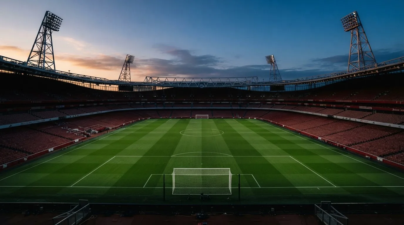 An empty football stadium with floodlight masts at dusk