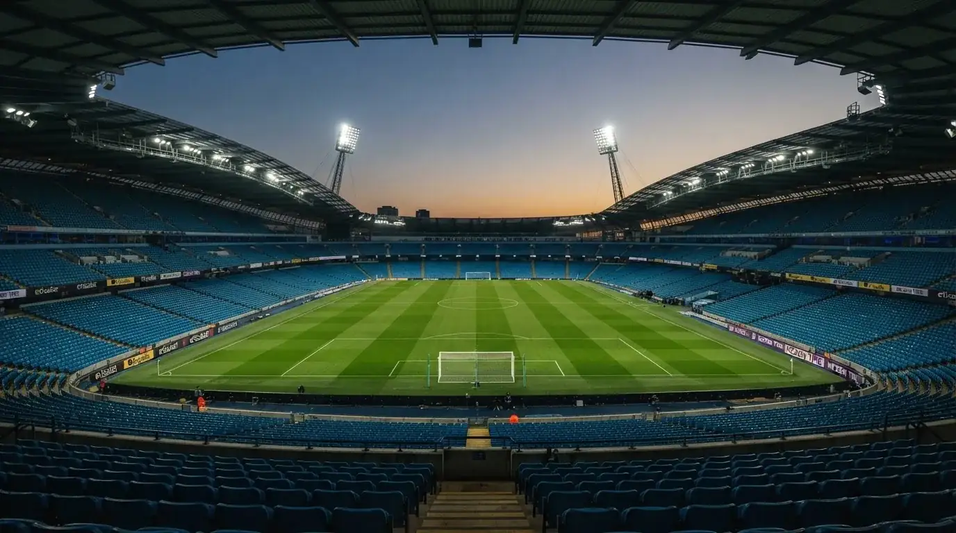 An empty football stadium with floodlight masts at dusk