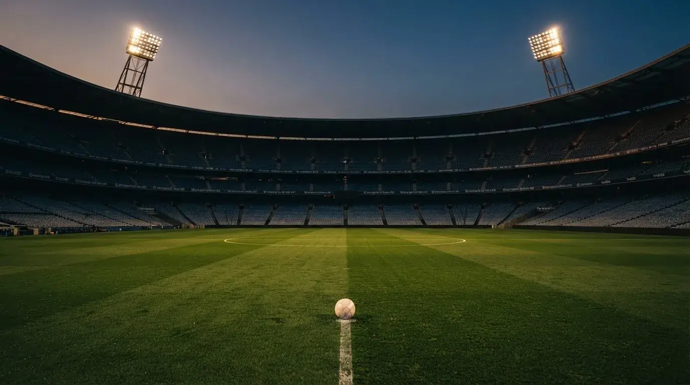 An empty football stadium with floodlight masts at dusk