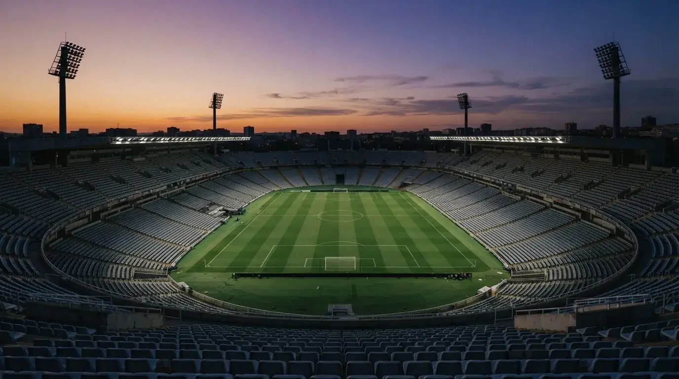 An empty football stadium with floodlight masts at dusk