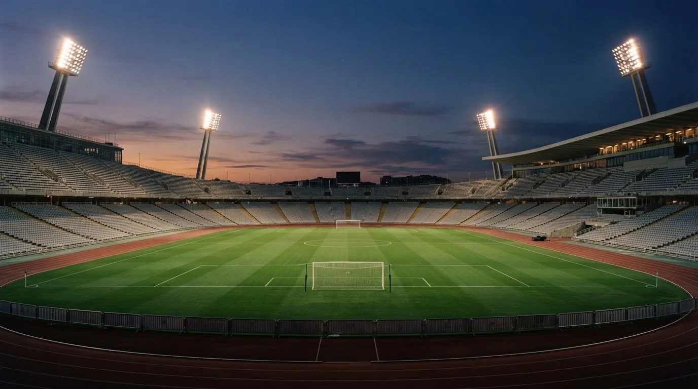 An empty football stadium with floodlight masts at dusk