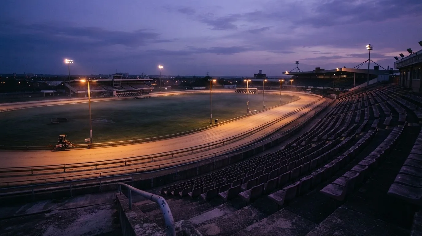 An empty football stadium with floodlight masts at dusk