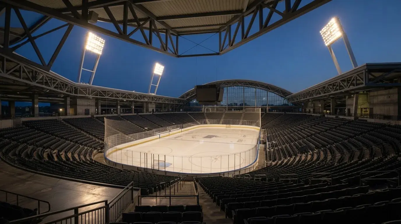 An empty football stadium with floodlight masts at dusk