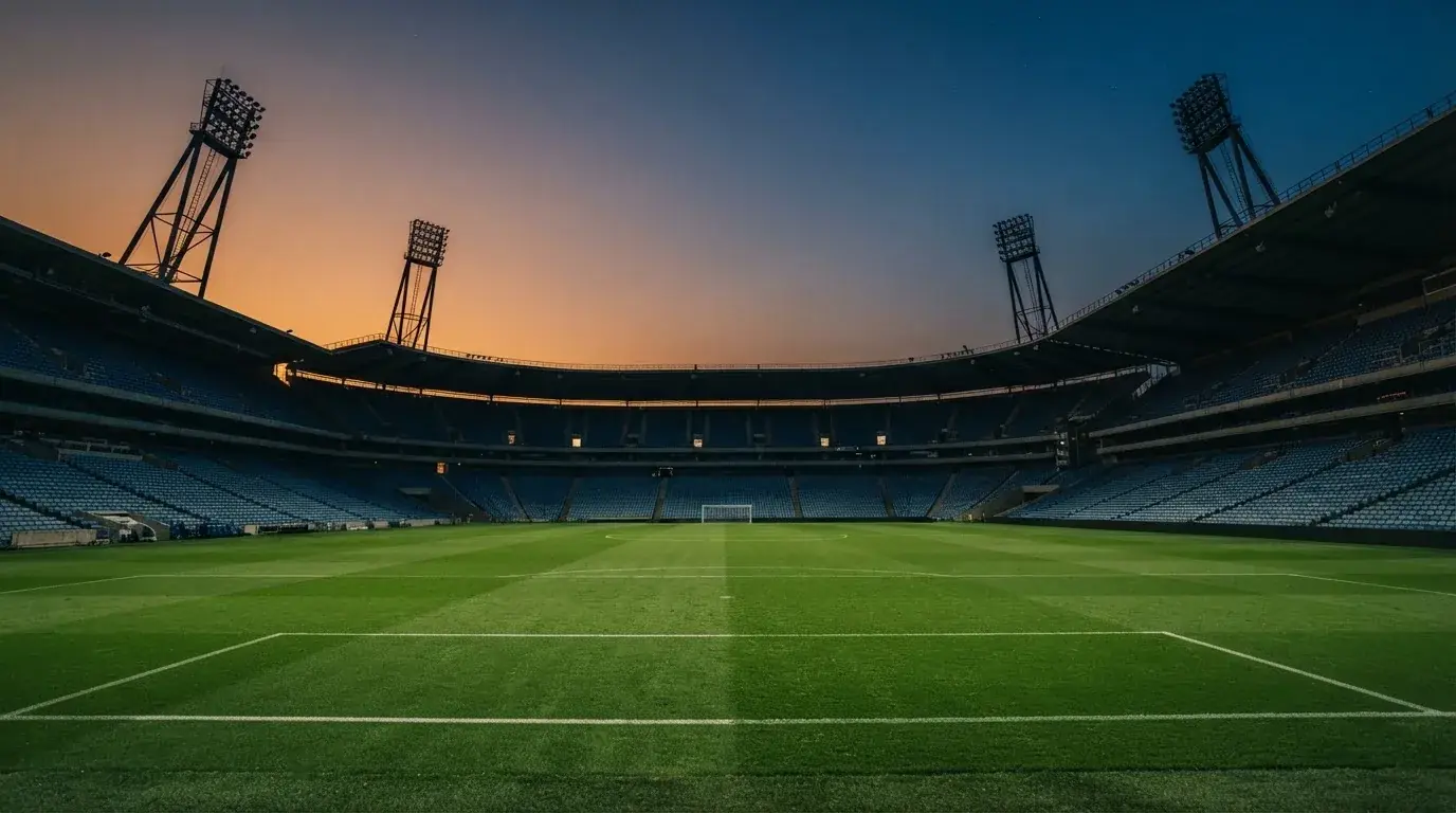 An empty football stadium with floodlight masts at dusk