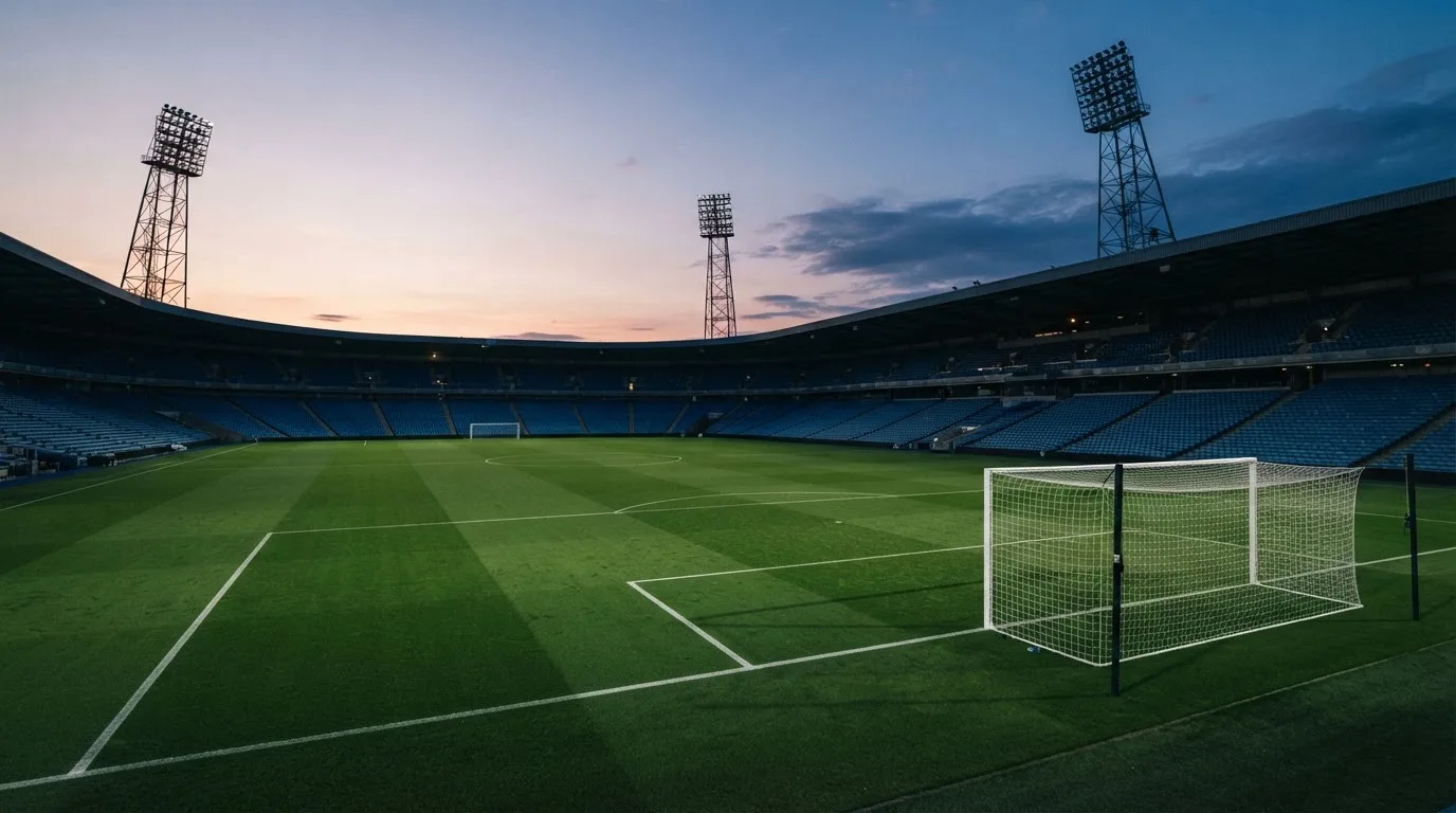 An empty football stadium with floodlight masts at dusk