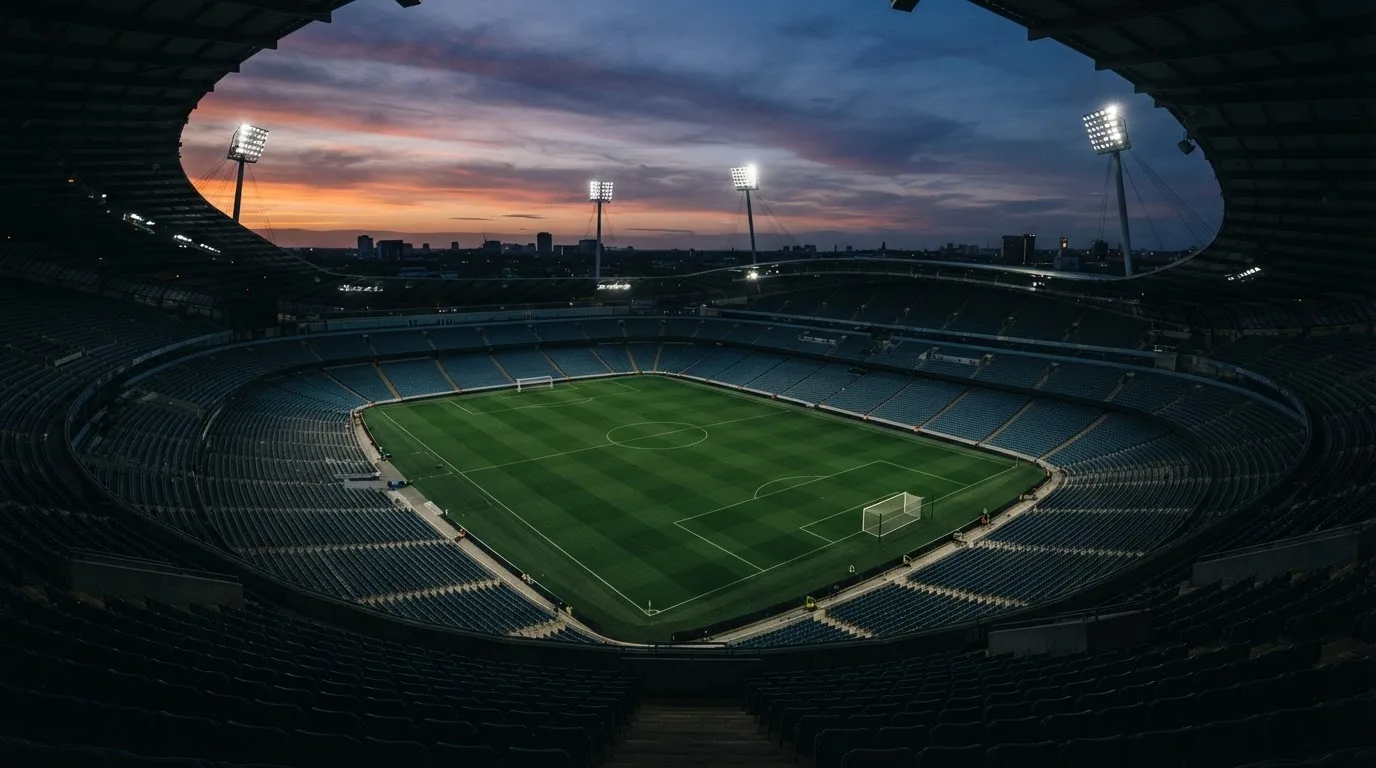 An empty football stadium with floodlight masts at dusk