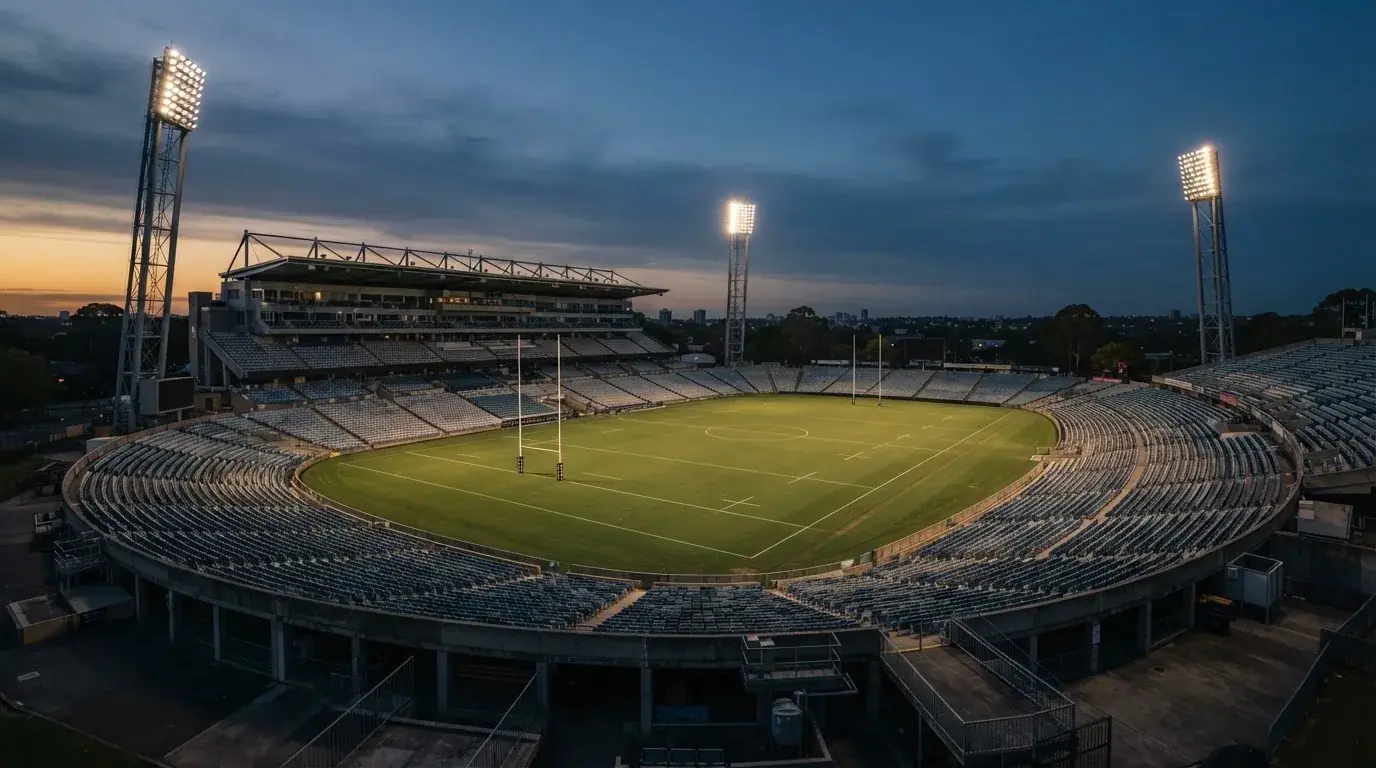 An empty football stadium with floodlight masts at dusk