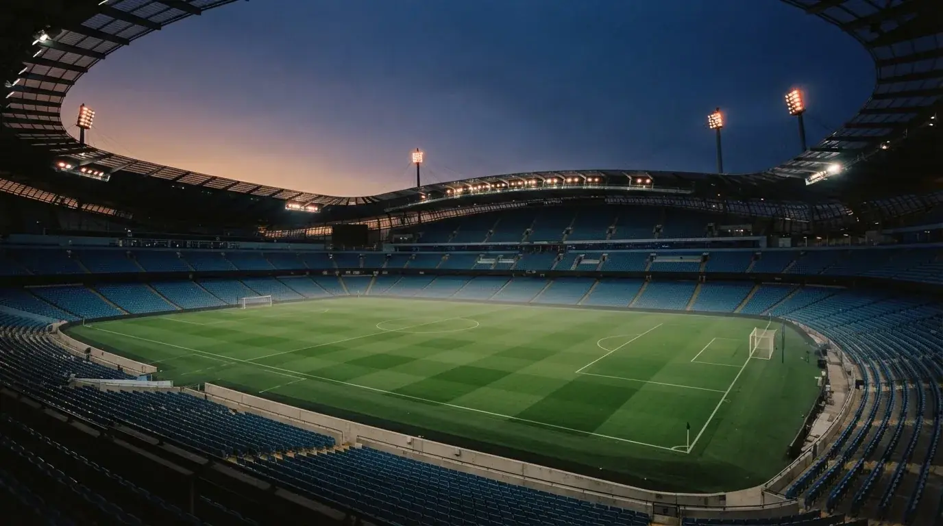 An empty football stadium with floodlight masts at dusk