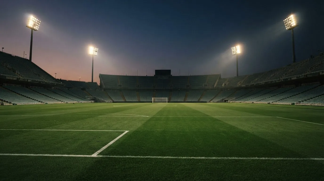 An empty football stadium with floodlight masts at dusk